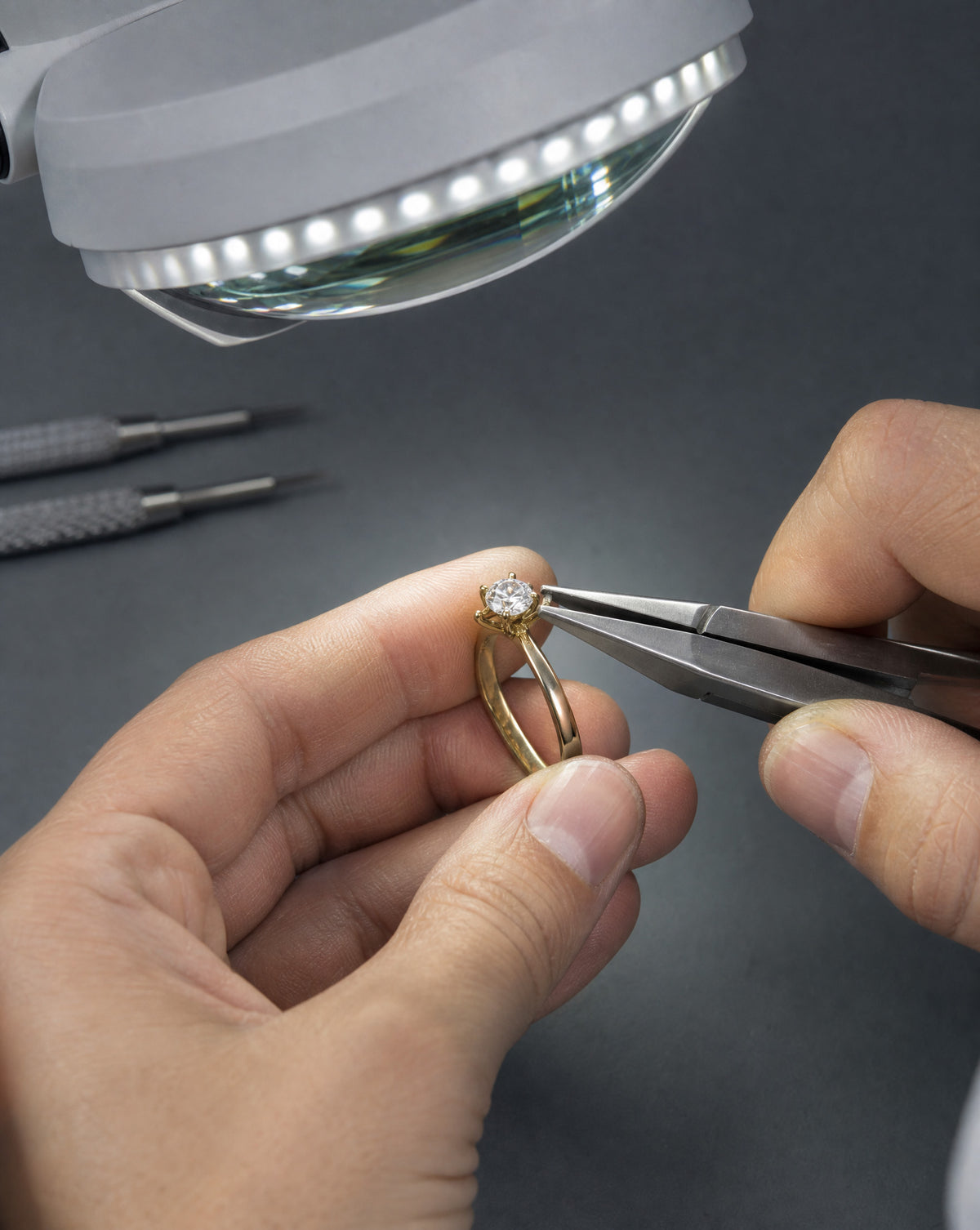 Jeweller repairing a diamond ring with tweezers under a magnifier, Hatton Garden