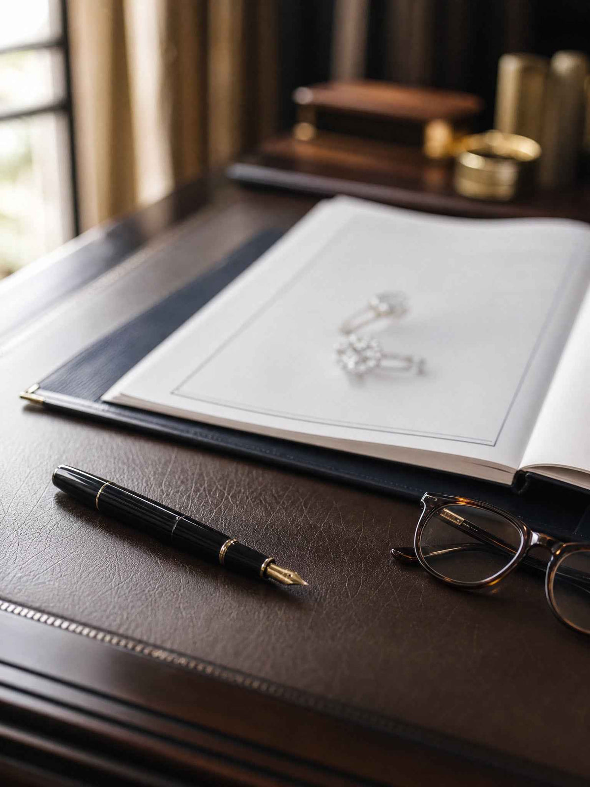 Valuation report with diamond earrings, fountain pen and glasses on a leather desk