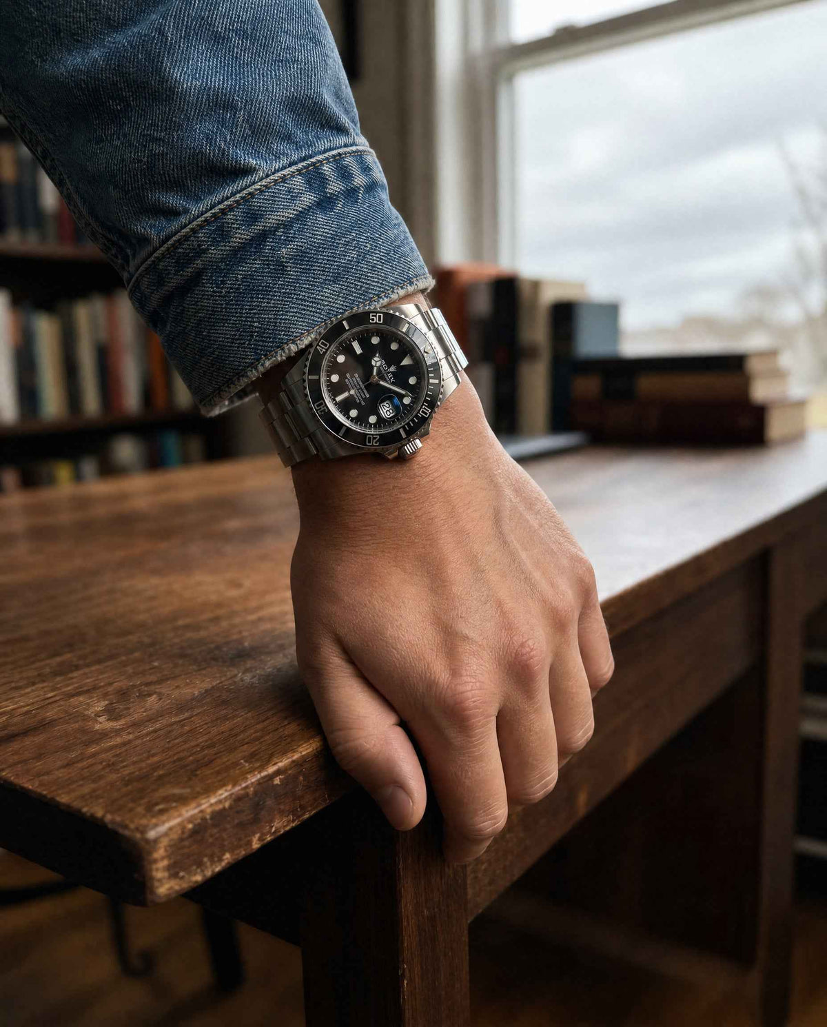 Man wearing a steel dive watch at a wooden desk, watch valuation for insurance